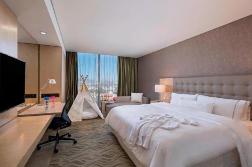 a bedroom with a large bed with a desk and a computer at The Westin Guadalajara in Guadalajara