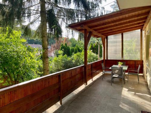 Un porche de madera con una mesa y sillas. en BONI Apartman, en Miskolctapolca