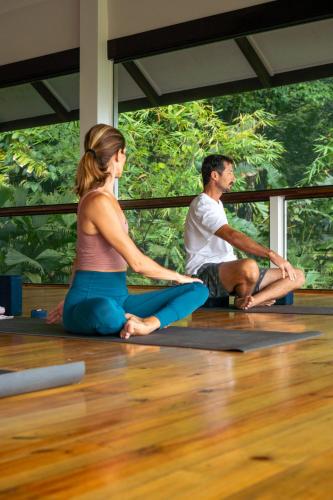 a man and a woman sitting on the floor in a yoga class at Roam Yoga & Wellness Lodge in Bocas del Toro