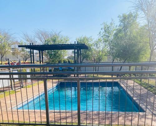 uma piscina atrás de uma cerca com um portão em Jackal Creek em Joanesburgo