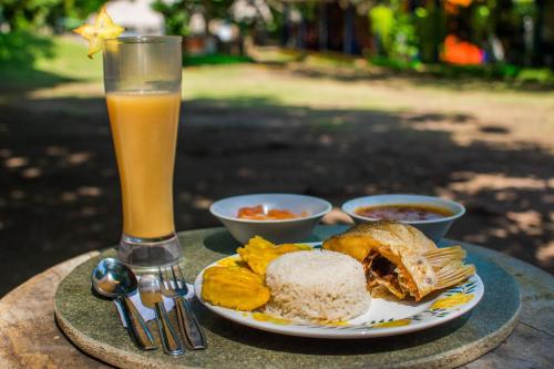 a plate of food and a glass of orange juice at Cabañas Los Venaos in San Bernardo del Viento