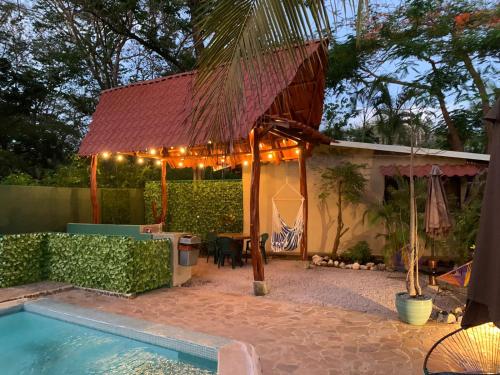 un patio trasero con piscina y un pabellón con luces en Casa Tropical Playa Grande en Cuajiniquil
