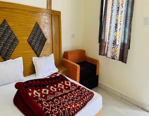 a bedroom with a bed and a chair in it at CRK Palace Kedarnath by StayApart in Trijugi Nārāyan