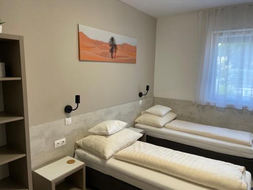 a room with three beds and a window at RoyalHill Apartman in Vonyarcvashegy