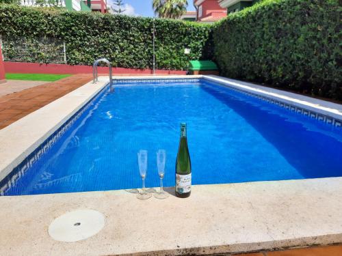 a bottle of wine and two glasses next to a swimming pool at URBANIZACION MIRAMAR PENISCOLA in Peñíscola