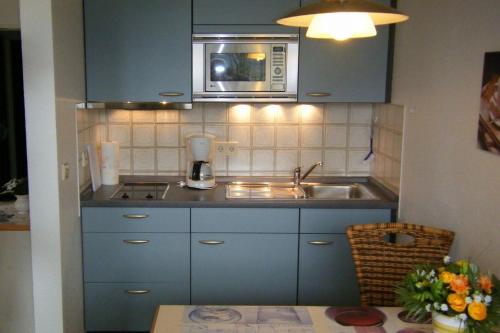 cocina con armarios azules, fregadero y microondas en Appartment 1022, Missen-Wilhams en Missen-Wilhams