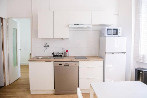 a kitchen with white cabinets and a white refrigerator at Latitude - Appartement proche Notre Dame de la Garde in Marseille