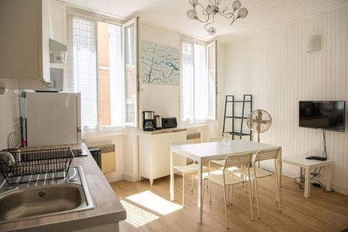 una cocina con mesa blanca y sillas. en Latitude - Appartement proche Notre Dame de la Garde, en Marsella