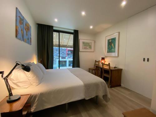 a bedroom with a bed and a desk and a window at CaLoura 76 in Lagoa