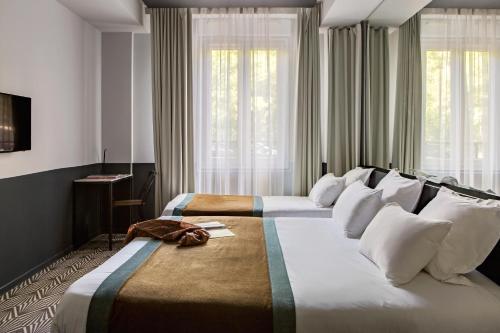 two beds in a hotel room with windows at Hôtel Gaston in Paris