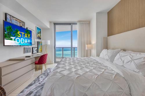 een slaapkamer met een groot bed en een televisie bij Seashore Resort #3805 - 2 BEDROOM RIGHT ON THE BEACH DIRECT OCEAN-VIEW WITH AMENITIES ON THE ROOFTOP in Hollywood