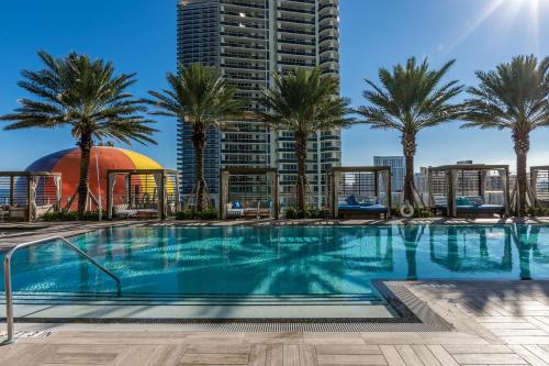 a swimming pool with palm trees and a tall building at Dreamy Beachside Living - Direct Oceanview 2BR 2BA for the Perfect Escape in Hollywood