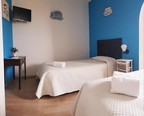 a room with two beds and a table and a tv at Alcamim Guesthouse in Elvas