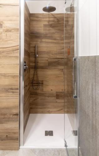 a shower with wooden walls and a glass door at Corte Masnate "Arancio" - Lenno by LoveComo in Lenno
