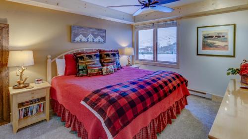 a bedroom with a bed with a red comforter and a window at Bear Claw 104 - Bear Claw I Building in Steamboat Springs