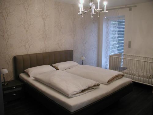 Schlafzimmer mit einem Bett mit weißer Bettwäsche und einem Kronleuchter in der Unterkunft Lifestyle Beauty & Wellness in Moosbach