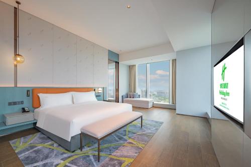 a bedroom with a bed and a flat screen tv at Holiday Inn Changchun Oriental Plaza by IHG in Changchun
