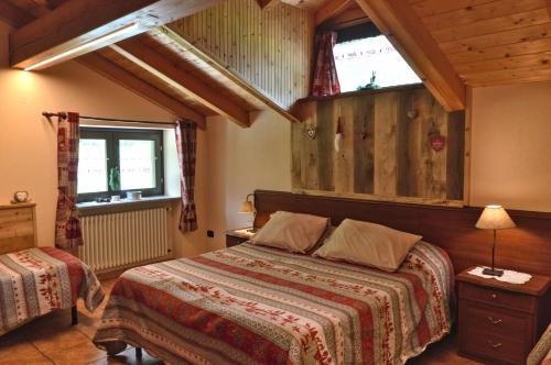 a bedroom with a bed and two windows in it at Appartamenti Luseney in Bionaz