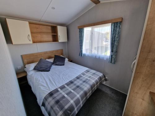 a small bedroom with a bed and a window at Seaside Holiday Home Inside a Resort in Selsey