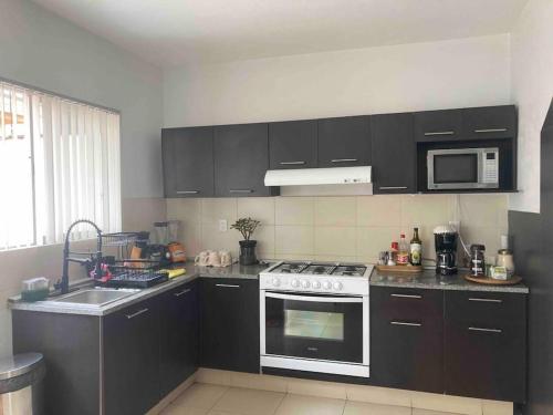 a kitchen with black cabinets and a white stove top oven at Casa acogedora frente a parque 2000 pegaso, Frac. Las Misiones 1 in Toluca