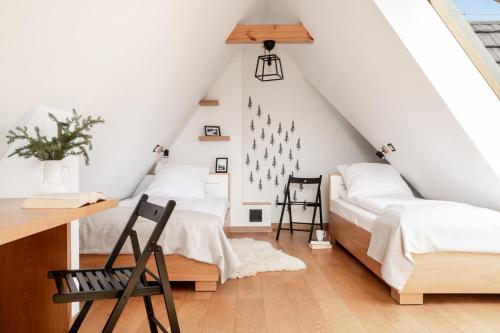 two beds in a attic bedroom with white walls at Mountain Base - Dwupoziomowy apartament "Przy lesie II" z prywatnym jacuzzi w Kościelisku in Kościelisko