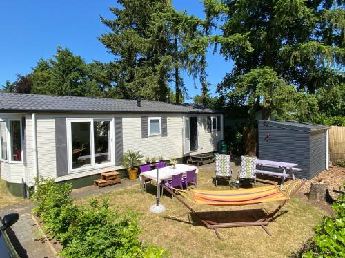 a caravan with a table and chairs in a yard at Ruim en modern chalet in de Veluwse bossen in Putten