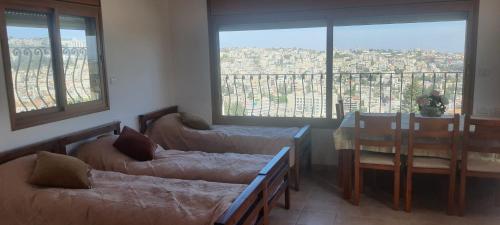 Zimmer mit 2 Betten, einem Tisch und einem Fenster in der Unterkunft Aida Magic of Nazareth - Guesthouse in Nazareth