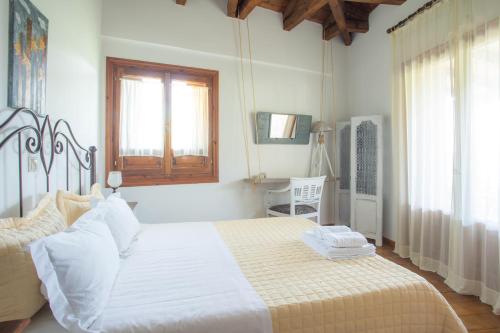 una camera da letto con un letto con lenzuola bianche e una finestra di Traditional family villa southern lefkada a Sívros