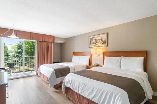 a hotel room with two beds and a large window at Hotel Bromont in Bromont