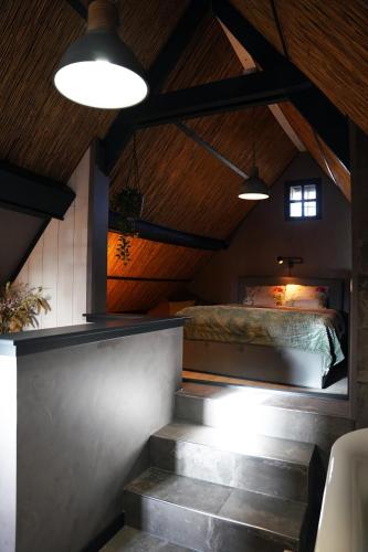 a bedroom with a bed and stairs in a room at Vakantiehuisje Tol Oost in Werkendam