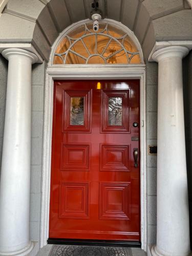 a red door in a building with two columns at Pring Guesthouse in Hamilton