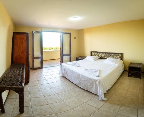 a bedroom with a large white bed and a bench at Aqua Villa by Garvetur in Beberibe
