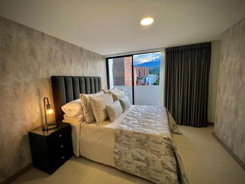 a bedroom with a large bed with a large window at Apartamentos Gema by Cadissa in Medellín