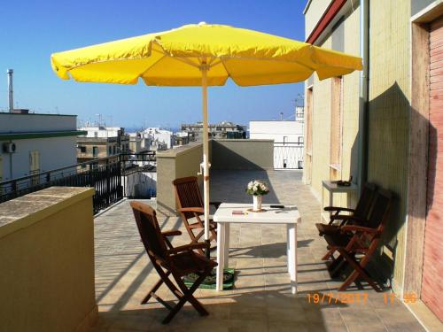 un tavolo e sedie sotto un ombrellone giallo su un balcone di City OVERLOOK a Ostuni