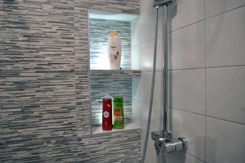ein Badezimmer mit Dusche und zwei Flaschen auf einem Regal in der Unterkunft Thea Home in Néa Karváli