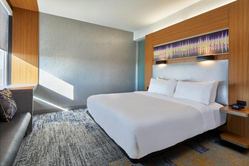 Cama blanca grande en habitación con sofá en Aloft Dulles Airport North en Ashburn