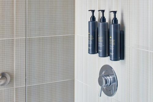 a bathroom with a shower with two bottles on the wall at Aloft Dulles Airport North in Ashburn