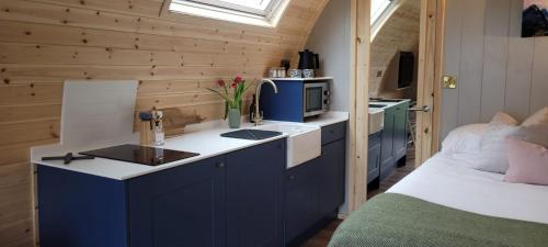 a kitchen with blue cabinets and a bed in a room at Odli Glamping - Deri in Welshpool