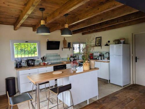 une cuisine avec une table et un réfrigérateur blanc dans l'établissement Maison de campagne Mon repos, à Courpignac