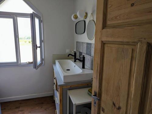 une salle de bain avec un lavabo blanc et une fenêtre dans l'établissement Maison de campagne Mon repos, à Courpignac