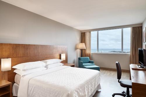 a hotel room with a bed and a large window at Sheraton Vitoria in Vitória