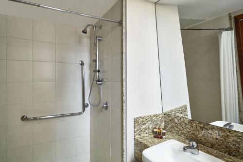 ein Bad mit einer Dusche, einem Waschbecken und einem Spiegel in der Unterkunft Sheraton Vitoria in Vitória