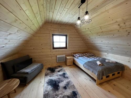 ein Schlafzimmer in einem Blockhaus mit einem Bett und einem Stuhl in der Unterkunft Śtyry Pory Roku in Bór Leśnica