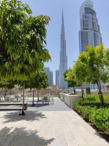 um parque com árvores, mesas e edifícios em Ultimate Stay / 5 min walk from Dubai Mall / Brand New / Downtown em Dubai