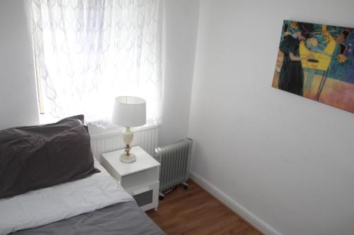 1 dormitorio con cama y mesita de noche con lámpara en Cozy light single bedroom, en Edgware