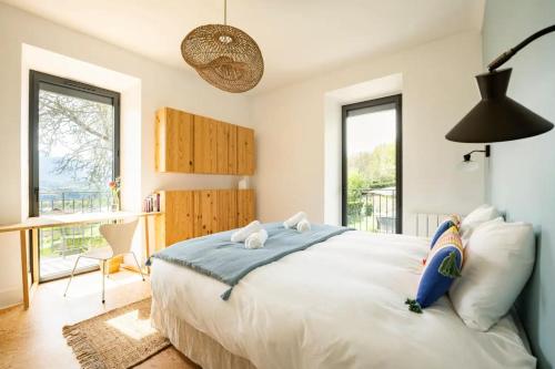 una camera da letto con un letto, una scrivania e finestre di Villa Côte des Vignes I Annecy 15' x Genève 30' a Charvonnex