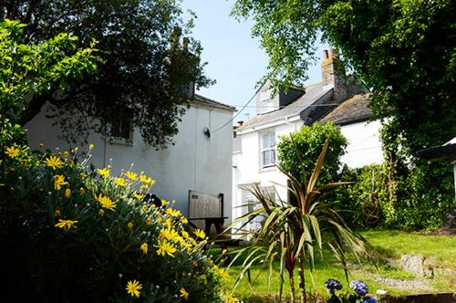 a white house with flowers in front of it at Lovely cottage with private garden in Penryn