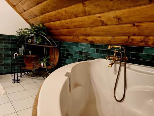 a white bath tub in a bathroom with green tiles at Zrubík pod Znievom (Log Cabin Zniev) 