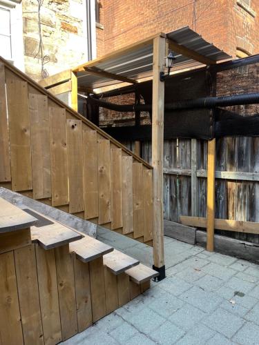 a wooden fence with benches in front of a building at Pring Guesthouse in Hamilton