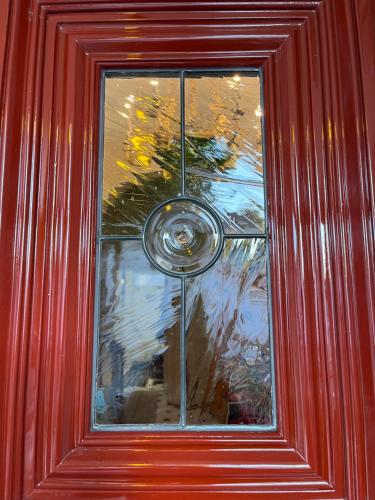 a glass window on a red door with a vase at Pring Guesthouse in Hamilton